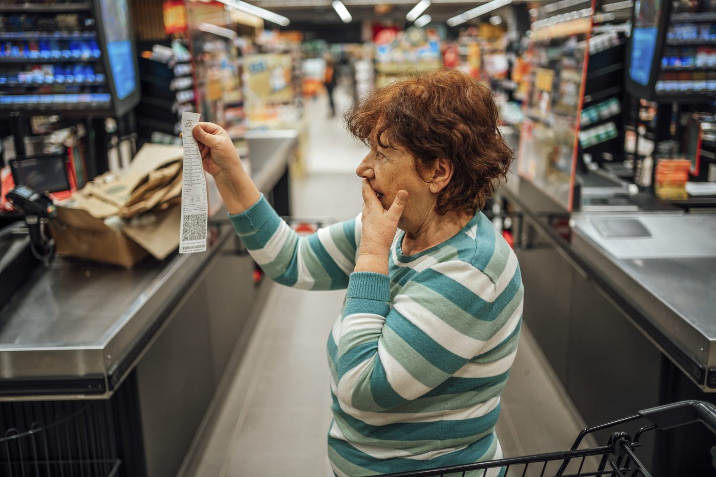 Senior woman feeling shocked because of the high amount on the bill in the supermarket