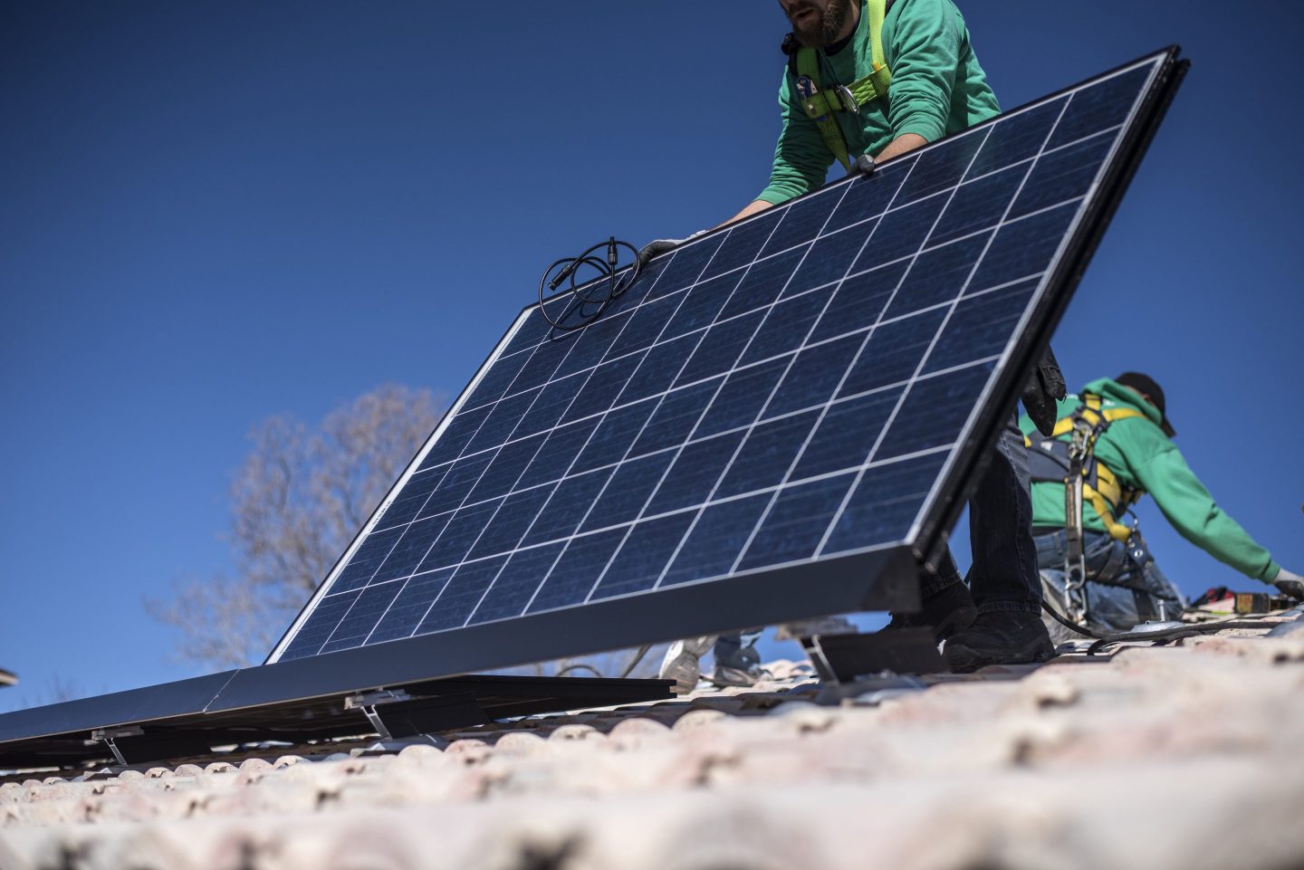 A worker lays down a solar panel on a rooftop during a SolarCity Corp. residential installation in Albuquerque, New Mexico, U.S., on Monday, Feb. 8, 2016. SolarCity is scheduled to release earnings figures on February 9. Photographer: Sergio Flores/Bloomberg via Getty Images